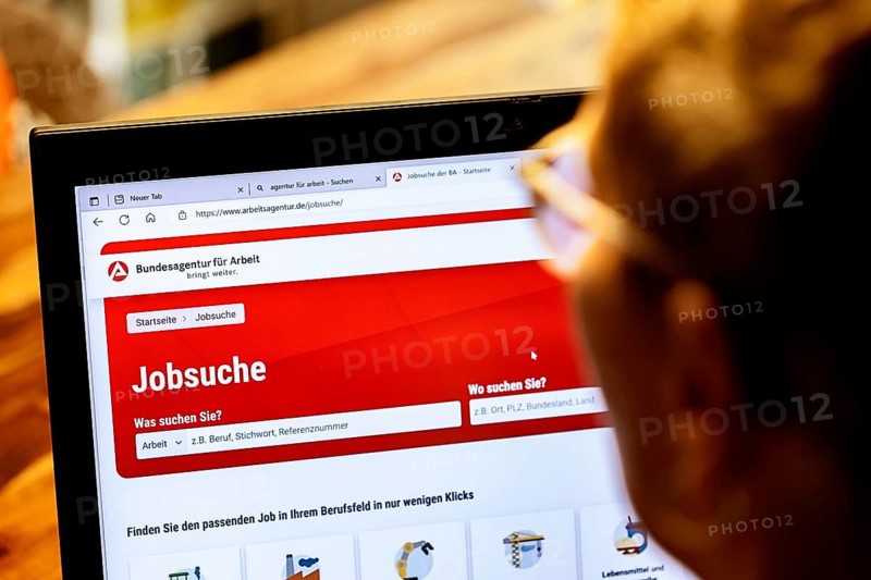 Woman with glasses looking for a job sits at home in front of her notebook and checks the internet site of the Federal Employment Agency for job offers