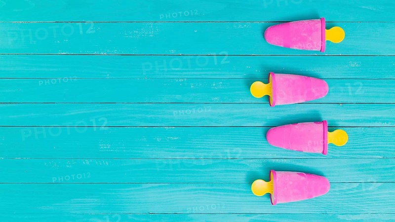 Bright pink frozen popsicles yellow sticks wooden background