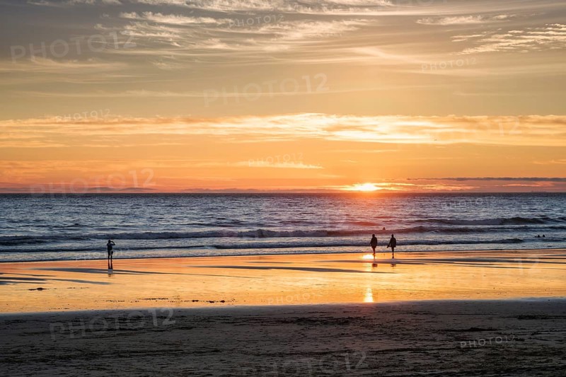 Atlantic ocean sunset with photographer silhouette taking images of surging waves at Fonte da Telha beach