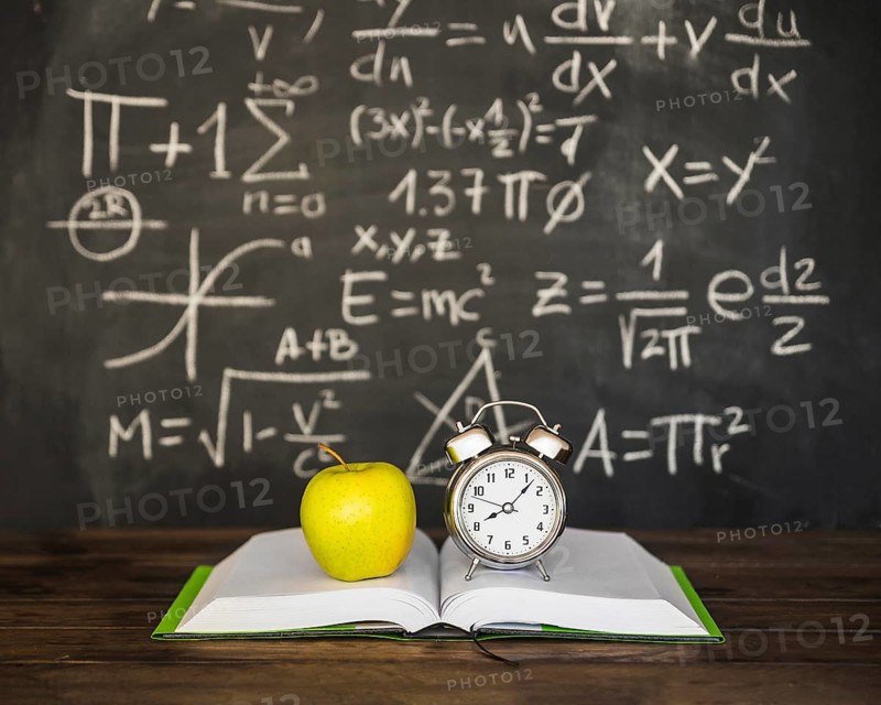 Book with apple alarm clocks near blackboard