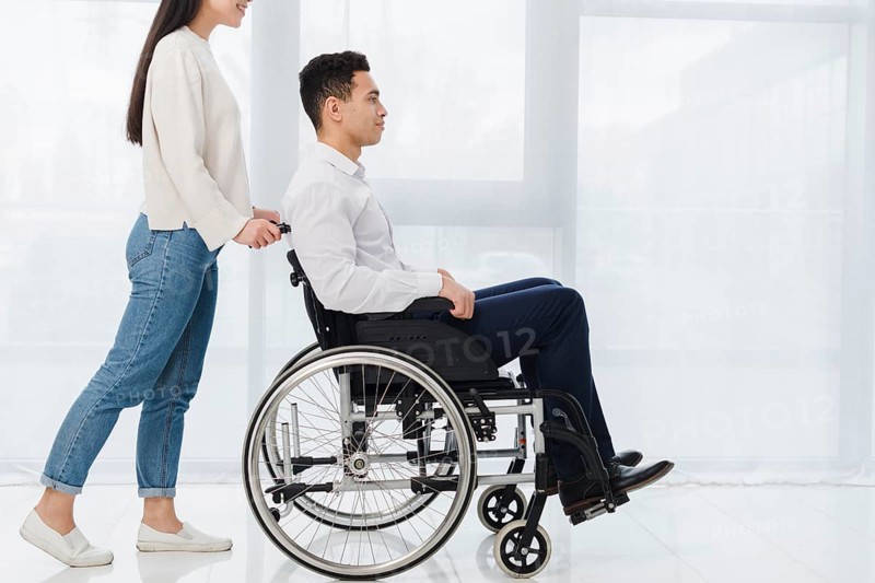 Smiling woman pushing young man sitting wheelchair