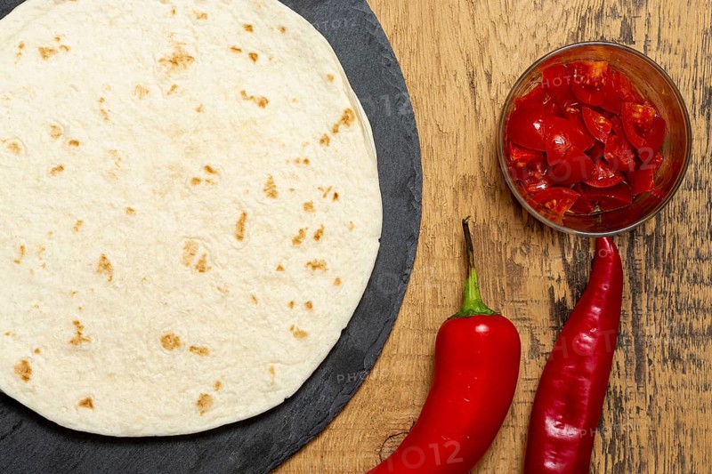 Tortilla near pepper sliced tomatoes