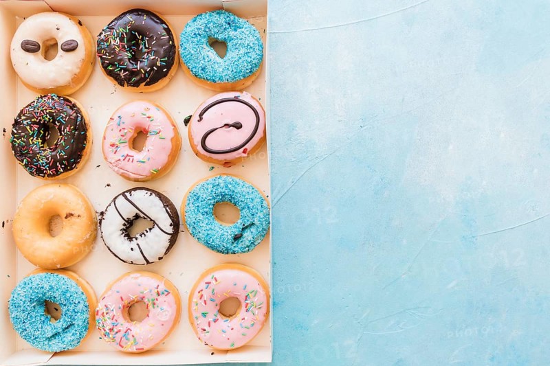 High angle view multi colored fresh donuts box blue background