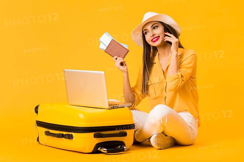 Smiley woman posing luggage while holding plane tickets passport