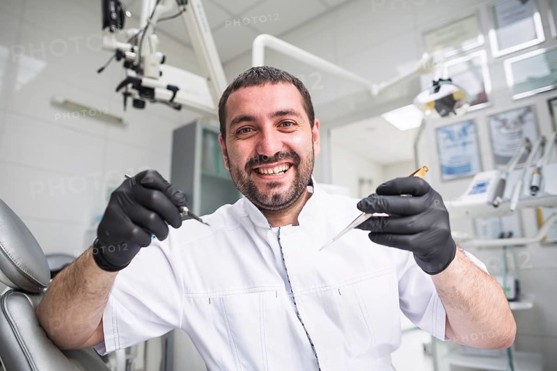 Portrait smiling male dentist with dental tools