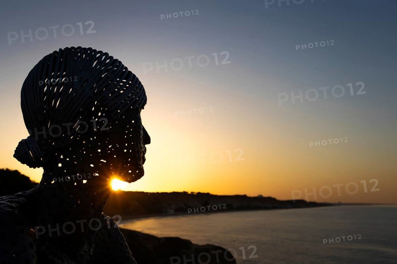 A metal sculpture by artist Carlos de Oliveira Correia looks out over the Atlantic Ocean at sunrise on the viewing platform at Olhos des Augua beach