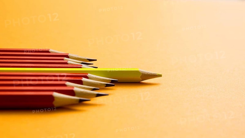 Yellow colored pencil lying red pencil against yellow background