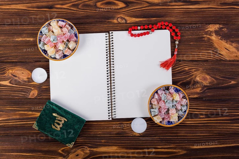 Overhead view spiral notebook with delight lukum bowls kuran red prayer beads wooden desk