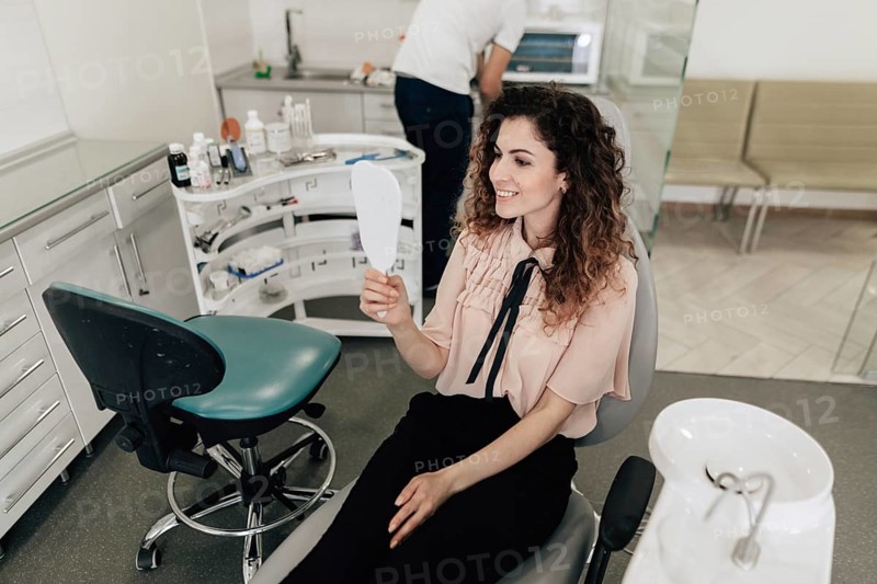 Woman looking teeth mirror dentist appointment