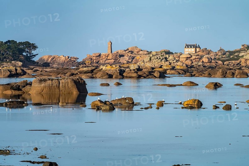 The rocks of the pink granite coast Cote de Granit Rose at the Baie de Sainte Anne near Tregastel with view of the Maison Gustave Eiffel and the lighthouse Phare de Ploumanac'h