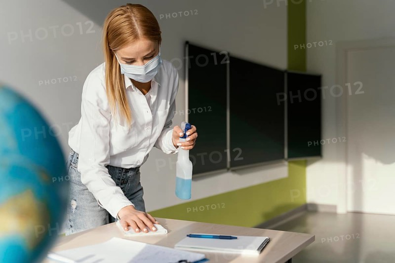 Female teacher disinfecting her desk classroom