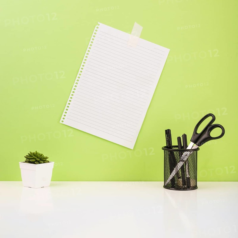 Pens scissors holder near paper stucked green wall