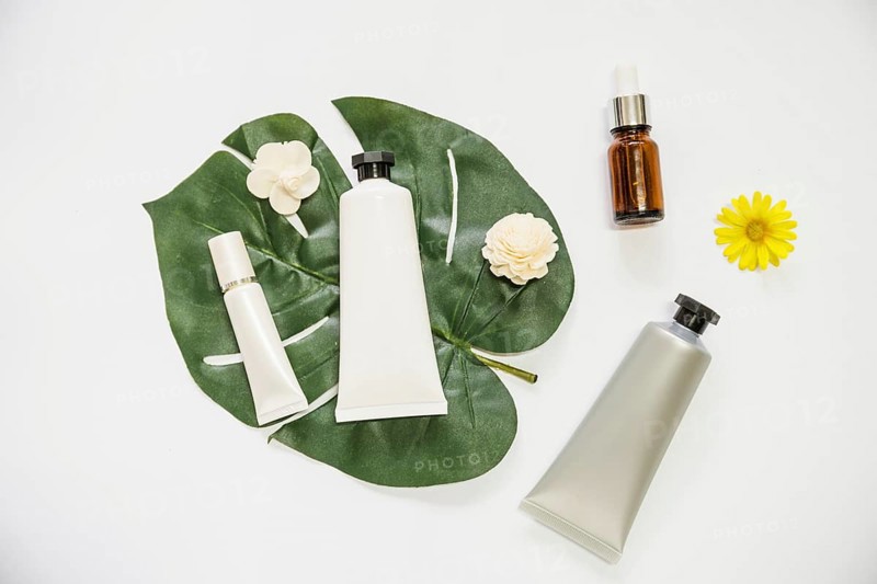 Cosmetic product flower monstera leaf essential oil bottle white background