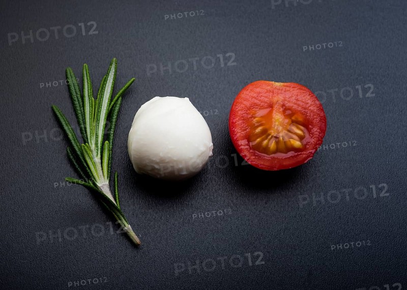 Green rosemary half cheery tomato mozzarella cheese black surface
