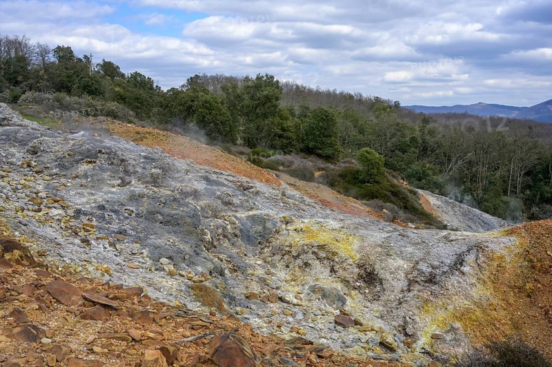 Colourful rubble deposits are surrounded by forest