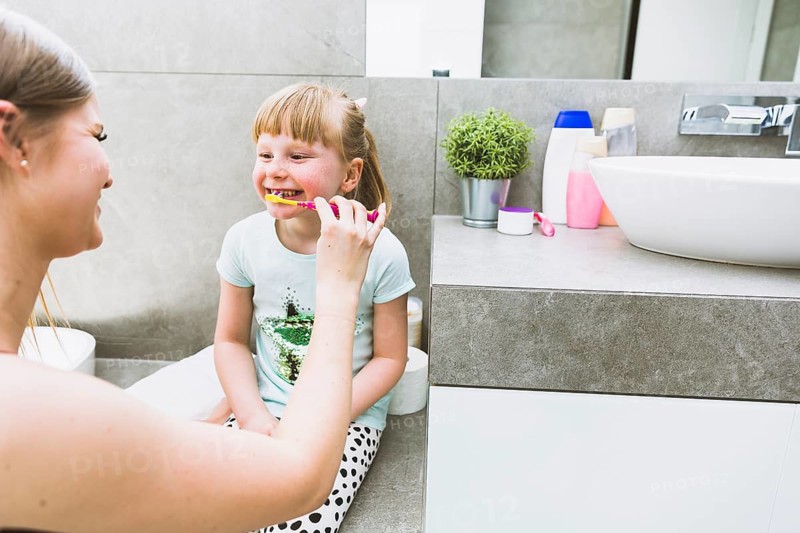 Mother brushing teeth daughter
