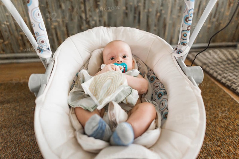 Cute baby with pacifier lying baby carriage home