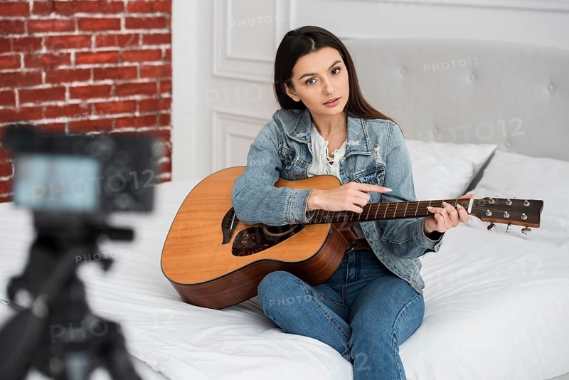 Young blogger teaching how play guitar