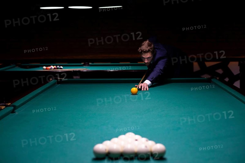Medium shot man suit playing billiard