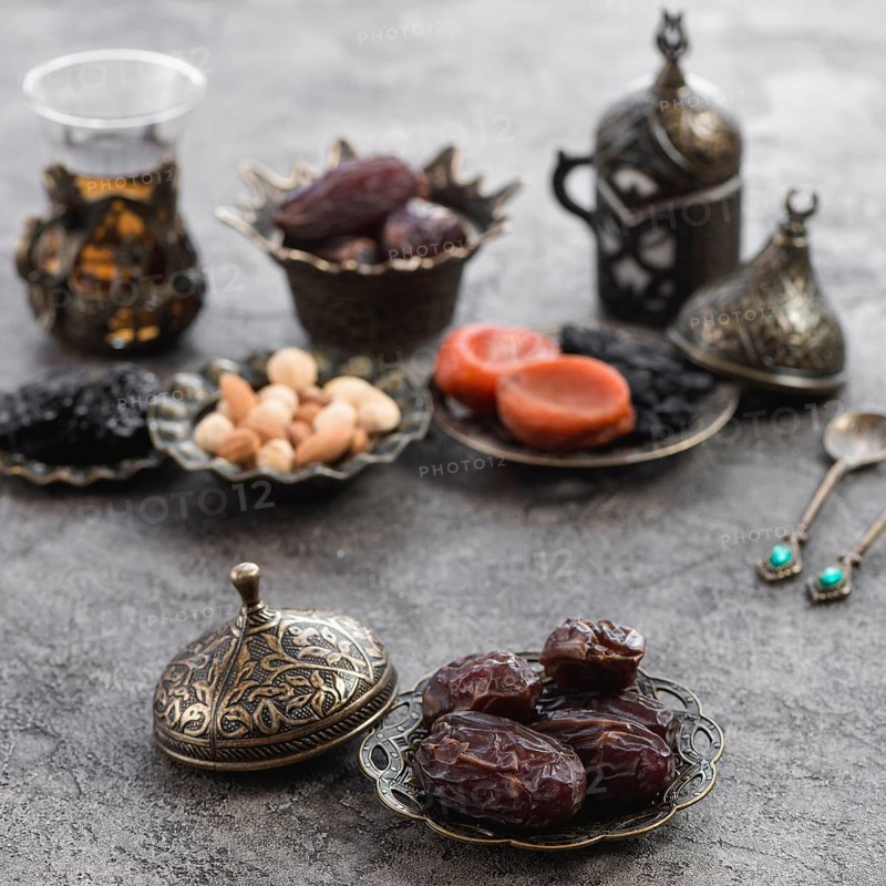 Organic dates bronze plate front dried fruits tea nuts concrete surface