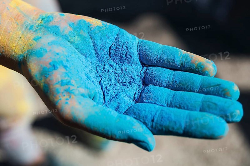 Close up person s hand holding blue holi color