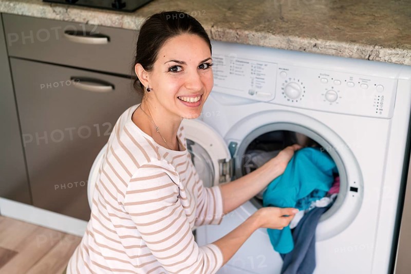 Lady putting clothes washing machine