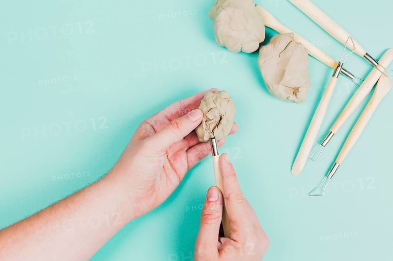Close up person s hand using sculpting tools mint green background