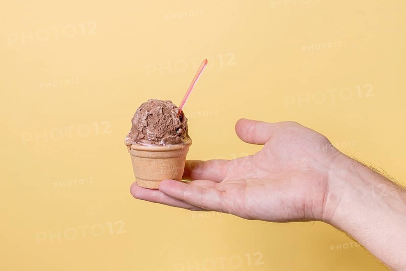 Hand holding little ice cream chocolate scoop