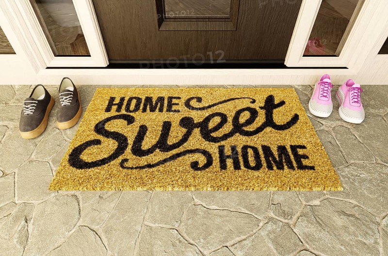 Home sweet home doormat with man and woman shoes on the porch at the front door