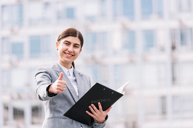 Modern businesswoman with clipboard outdoors