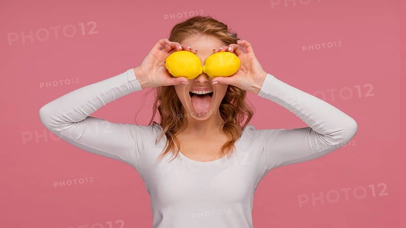 Portrait playful woman holding lemons laughs