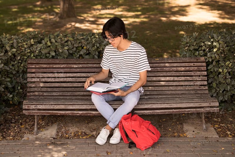 Asian teen man with textbook bench