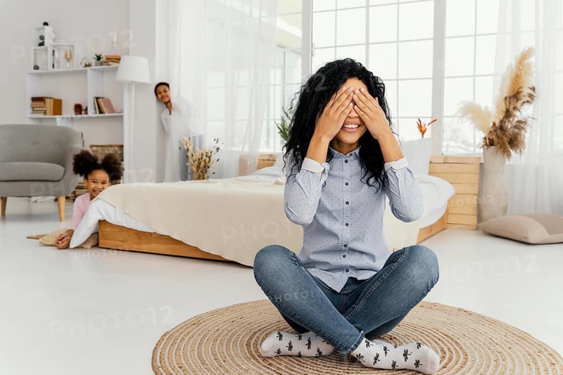 Front view smiley mother playing hide seek with her children home