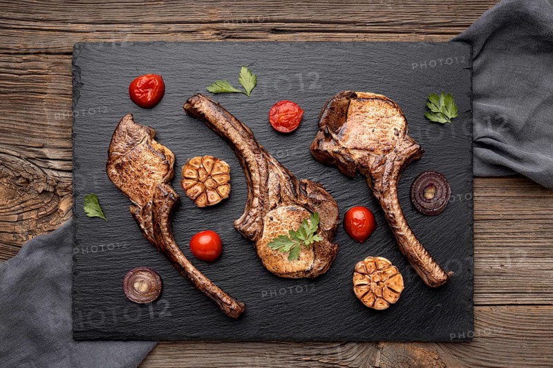 Wooden board with cooked meat vegetables