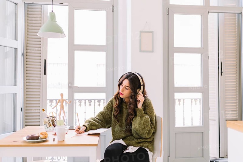 Focused woman drawing listening music