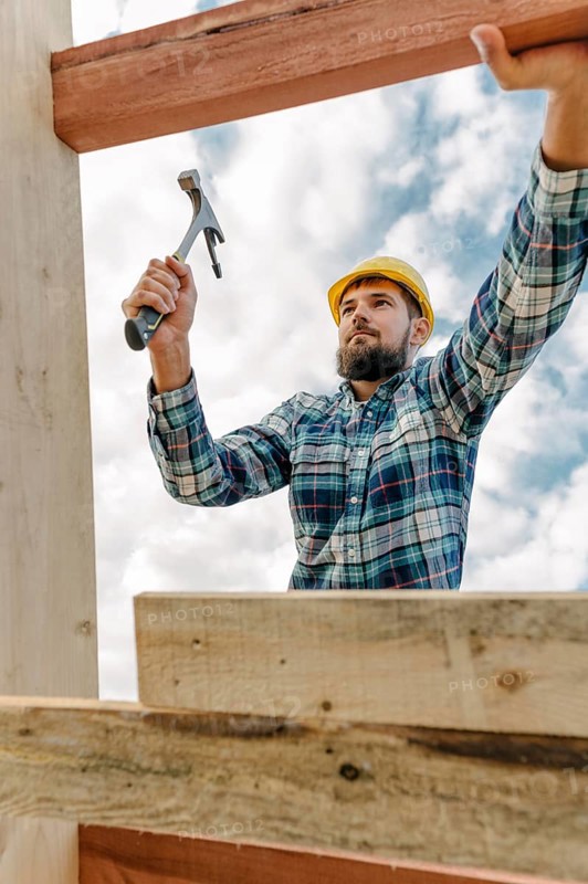 Construction worker with hammer hard hat building roof house