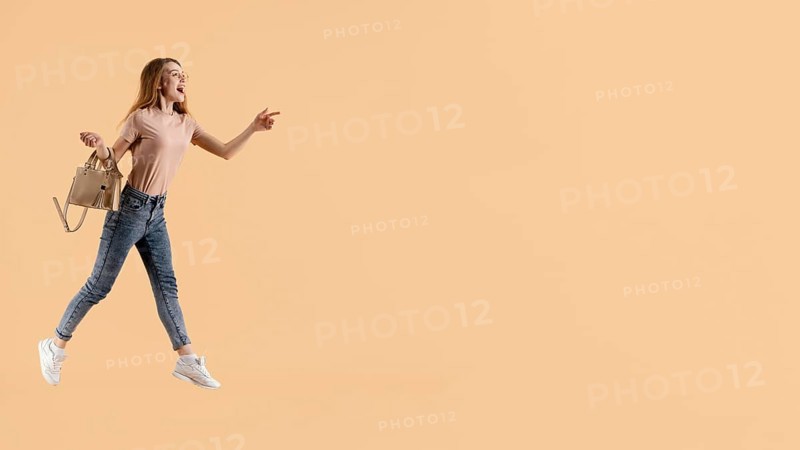 Young female model with hand bag jumping