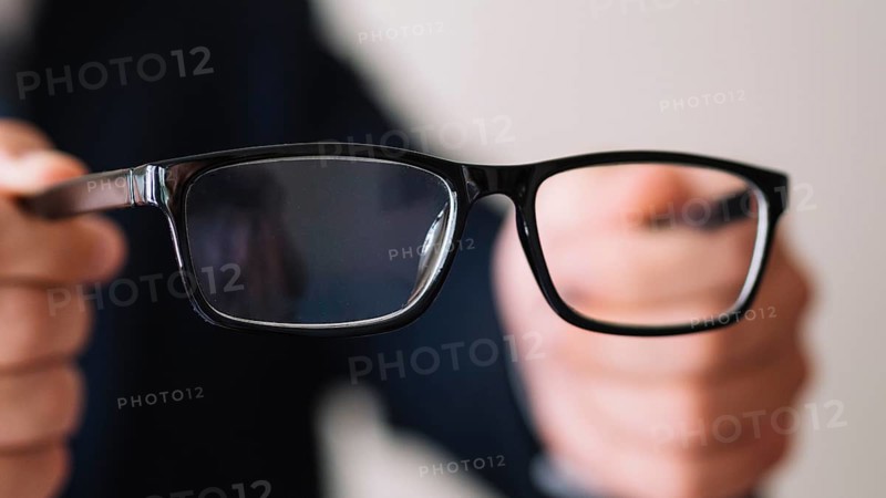 Man holding pair glasses with black frame