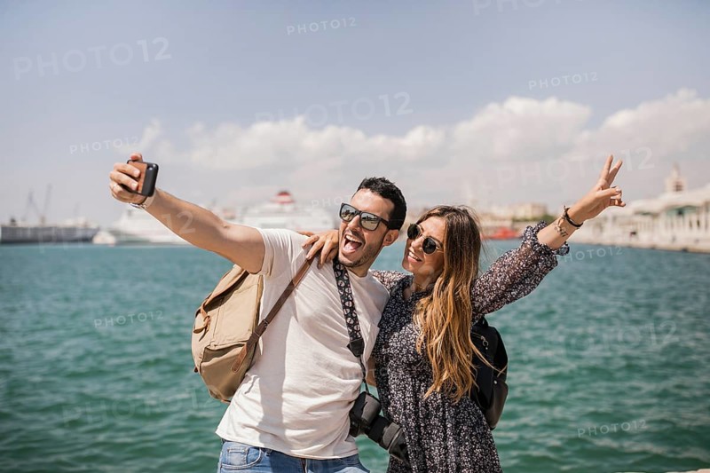 Woman making peace sign with her boyfriend taking selfie mobile