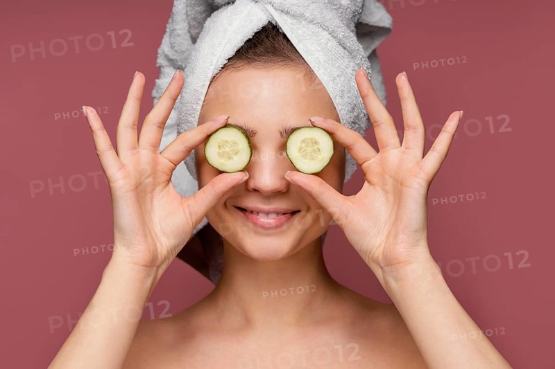 Beautiful woman using cucumber slices eyes