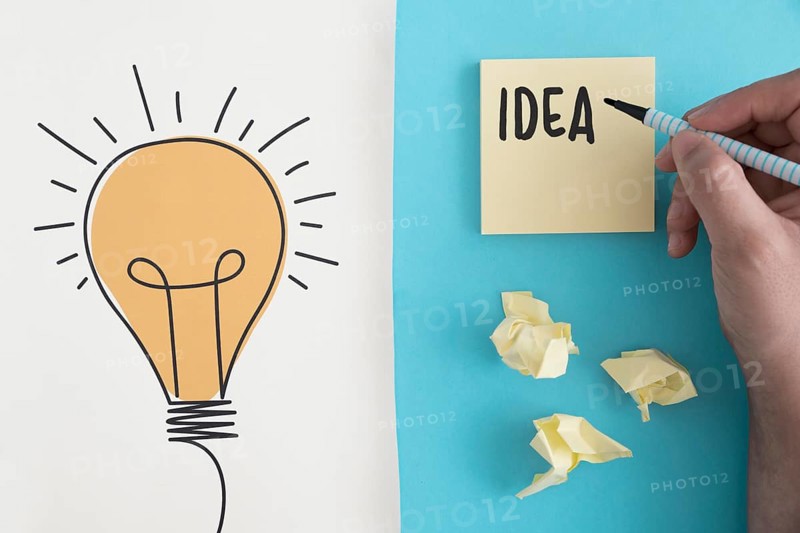 Idea text written with felt pen crumpled ball paper with hand drawn light bulb