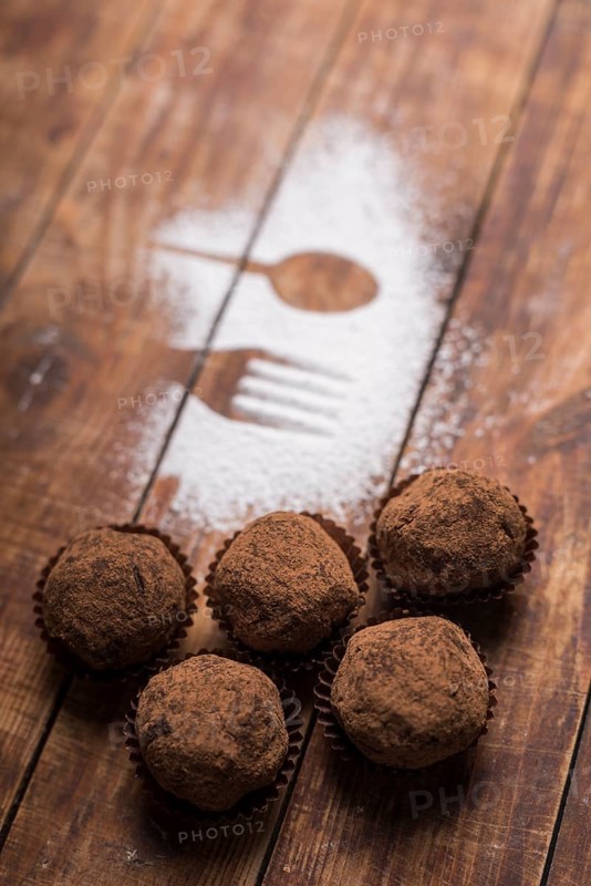 Homemade chocolate truffle candies with cocoa powder near spoon fork shape sugar powder
