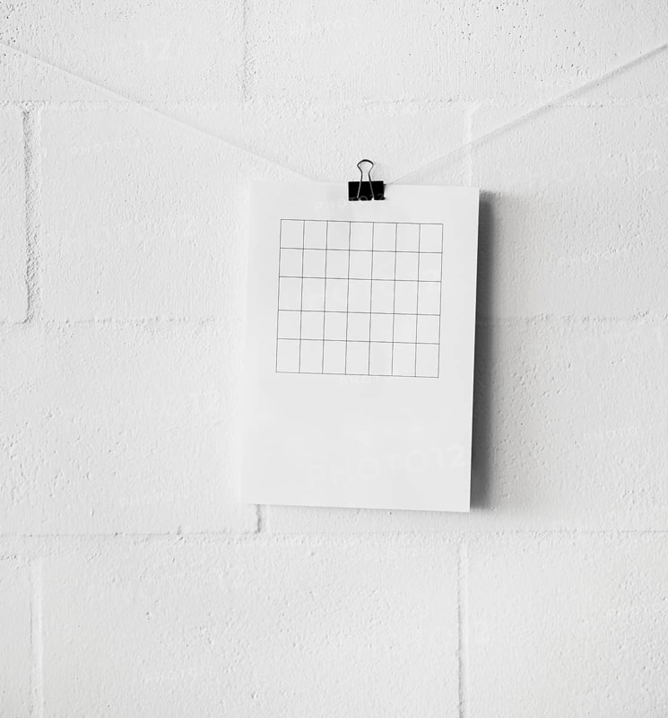 Am empty table paper attach string with paperclip against white wall