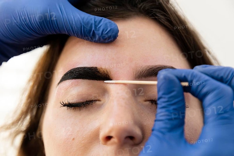 Woman getting eyebrow treatment from beautician