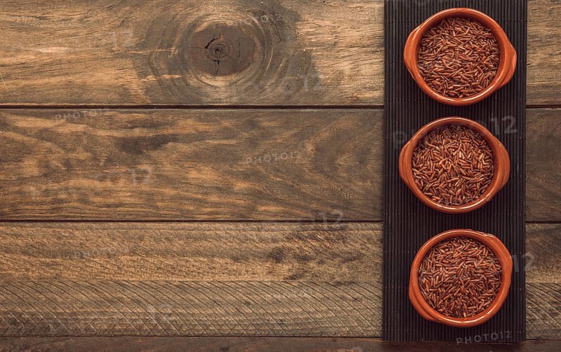 Uncooked red jasmine rice bowls placemat wooden background