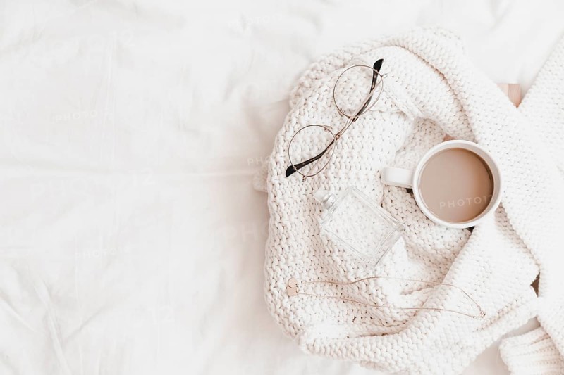 Hot drink necklace eyeglasses perfume sweater placed bedsheet