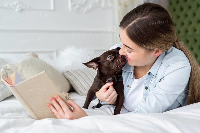 Close up girl reading bed with cute dog