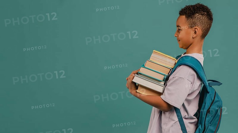 Side view child holding pile books