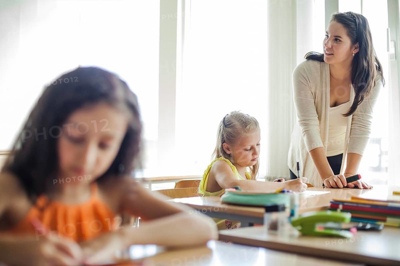 Female teacher leaning upon table looking away