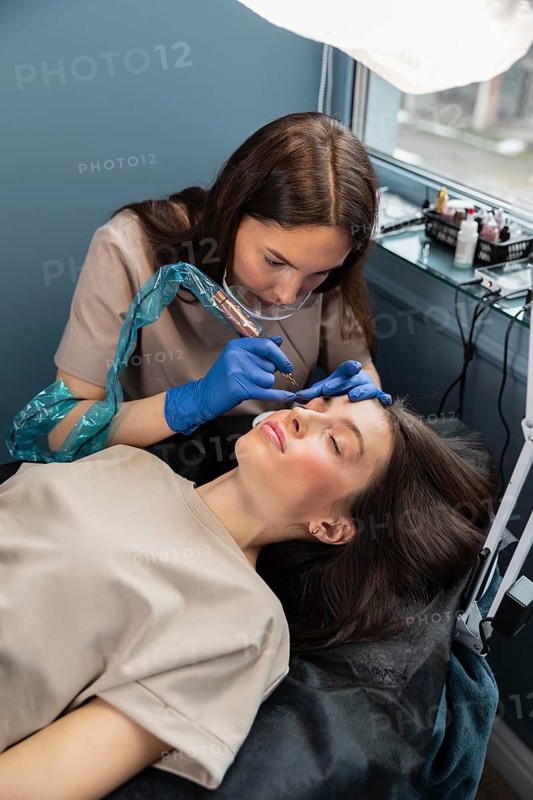Beautician doing eyebrow treatment her female client